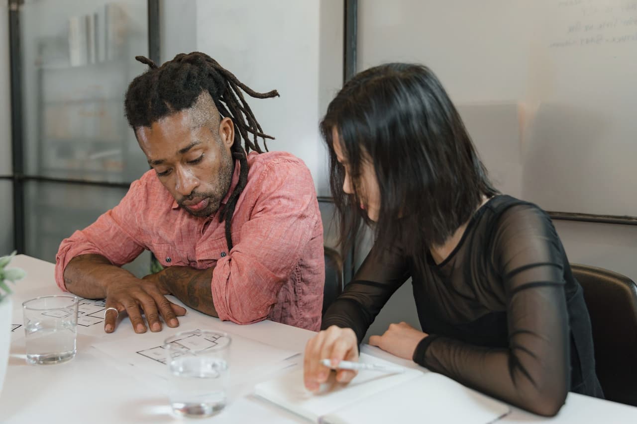 Two colleagues reviewing design plans together at a desk