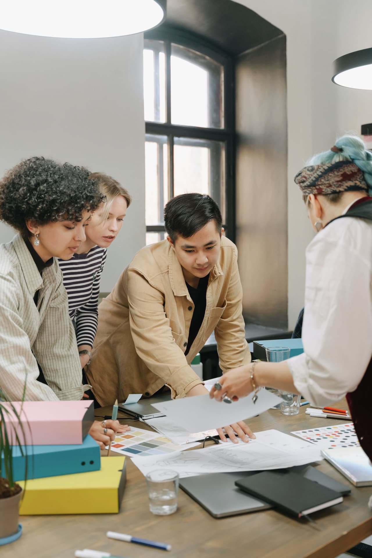 A creative team gathered around a table reviewing printed concepts and notes in a bright office