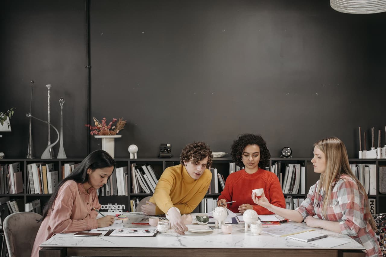 Team members working together at a long table in a dark-walled studio